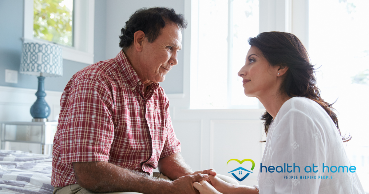 A daughter who is caregiving for her dad who has Alzheimer’s disease, lovingly holds his hands.